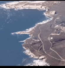 an aerial view of a coastline with a large body of water in the background