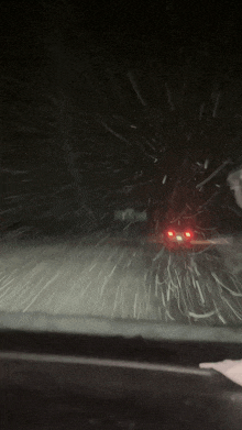 a car is driving through a snowy road at night