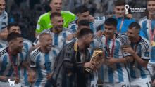 a group of soccer players celebrate with a trophy in front of a sign that says fifa world cup 2022