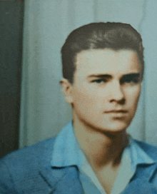 a close up of a man 's face with a blue shirt on