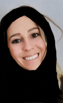 a woman wearing a black scarf around her head smiles