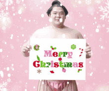 a sumo wrestler is holding a sign that reads merry christmas