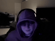 a person wearing headphones and a hoodie is sitting in front of a computer .