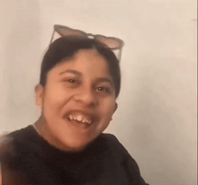 a young girl wearing sunglasses and a black shirt is smiling .