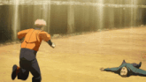 a man in an orange shirt is running away from another man laying on the ground