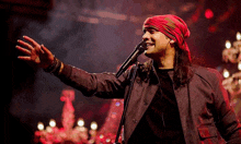 a man singing into a microphone with a red bandana on his head