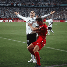 two men are playing soccer on a field with their arms in the air .