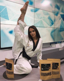 a woman in a taekwondo uniform is kneeling next to a bag of detox tea