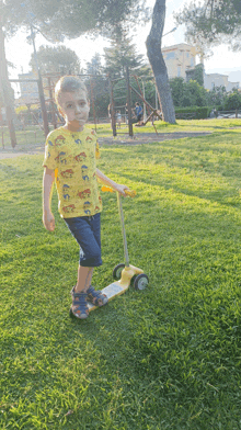 a young boy wearing a yellow shirt with elephants on it rides a yellow scooter