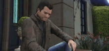 a man in a leather jacket is sitting in front of a building in a video game .