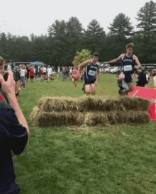 a man is taking a picture of a person jumping over hay bales while wearing a number 2 on their jersey