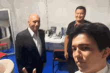 a man in a suit is taking a selfie with another man in a room .