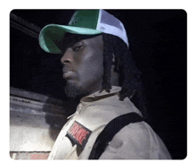 a man with dreadlocks wearing a green hat and a patch that says empire