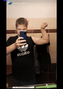 a man is taking a picture of himself in a bathroom with a shirt that says abbibo