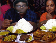 a man and woman sit at a table with plates of food