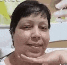 a close up of a woman 's face with her hand on her chin and smiling .