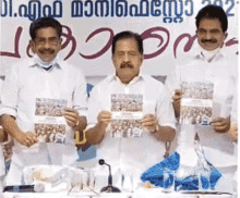 a group of men are posing for a photo in front of a sign that says ' malayalam ' on it