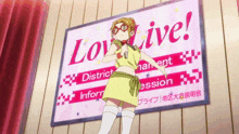 a girl in a yellow dress is standing in front of a sign that says love live