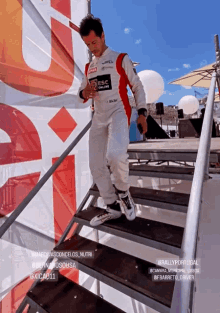 a man in a race suit climbs a set of stairs in front of a banner that says rally portugal