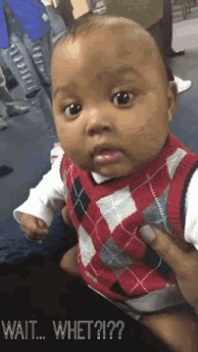 a baby in a plaid vest is being held by a woman and says wait whet