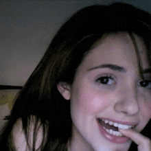 a close up of a woman 's face with her hand in her mouth