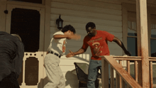 a man in a red shirt that says ' texas rangers ' on it is standing on a porch