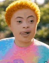 a woman with orange hair is sticking her tongue out