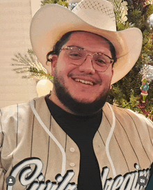 a man wearing a cowboy hat and glasses is wearing a jersey that says ' phoenix ' on the front