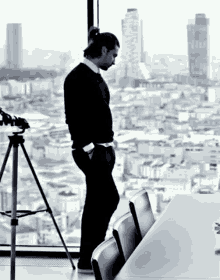 a man stands in front of a window with a view of a city and a building that says ' istanbul ' on it