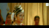 a woman is standing in front of a curtain wearing a crown and a flower in her hair .