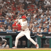 a baseball player is swinging a bat at a ball in front of a crowd at citizens bank park