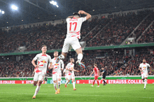 a soccer player with the number 17 on his shirt jumps in the air