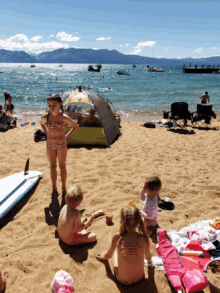 a girl in a bathing suit stands on a beach near a tent that says ' abercrombie & fitch ' on it