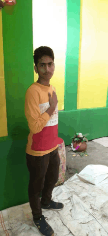 a young man stands in front of a green and yellow wall wearing a red shirt that says chase