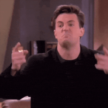 a man in a black shirt is making a funny face and making a funny face with his hands .