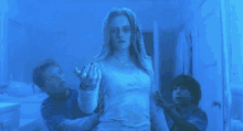 a woman in a white dress is surrounded by two boys in a blue room .