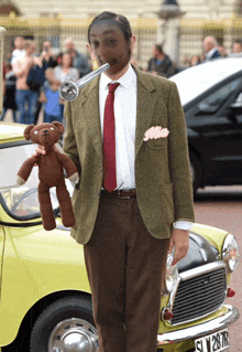 a man dressed as mr bean holding a teddy bear