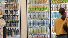 a woman is standing in front of a refrigerator filled with cans of soda including one that says lemon drop on it