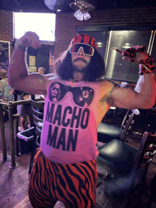 a man wearing a pink macho man tank top flexes his muscles