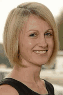 a woman with short blonde hair is smiling for the camera .