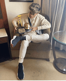 a man sits in a chair holding a trophy that says mvp on it