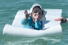 a little girl is floating on a white raft in the ocean