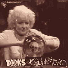 a black and white photo of a woman holding a crystal ball that says toks x goblintown on it