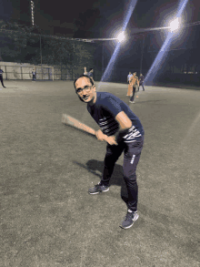 a man wearing a shirt that says ' cricket ' on it is swinging a bat