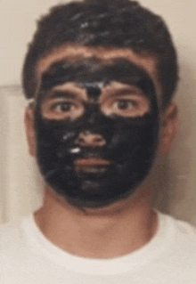 a man with a black mask on his face is wearing a white shirt