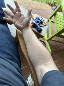 a man 's arm is shown with a nerf gun on the table in the background