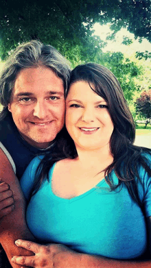 a man and a woman are posing for a photo and the woman is wearing a blue shirt