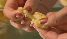 a close up of a person holding a piece of food with the words pão de queijo written above it