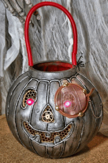 a metal pumpkin with a red handle and a light inside