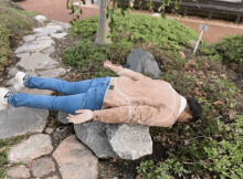a man laying on his back on a rock in a garden